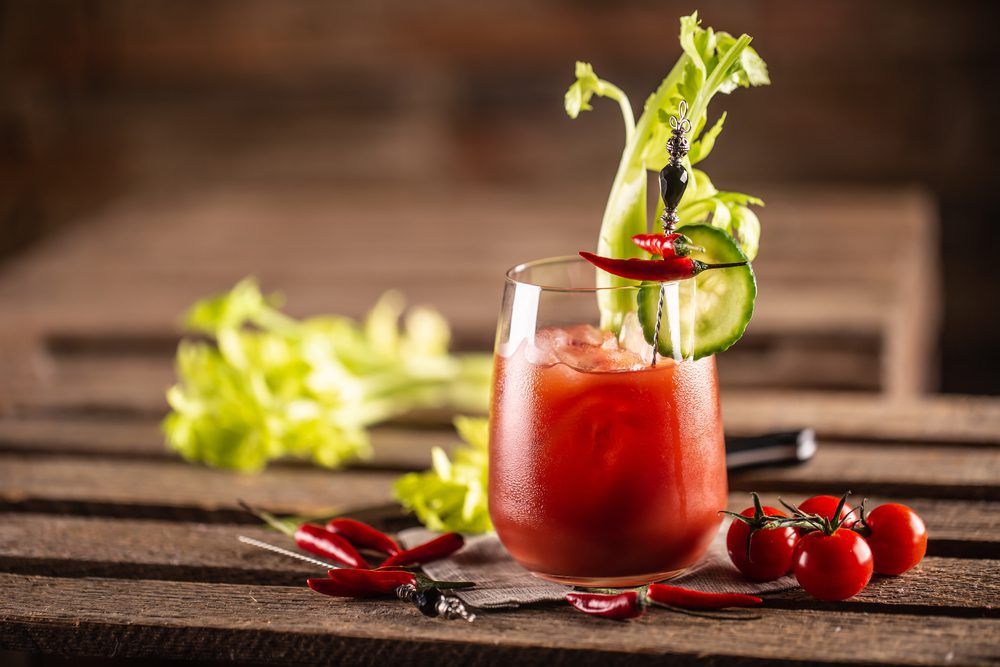 Glass with a bloody mary served, garnished by celery.